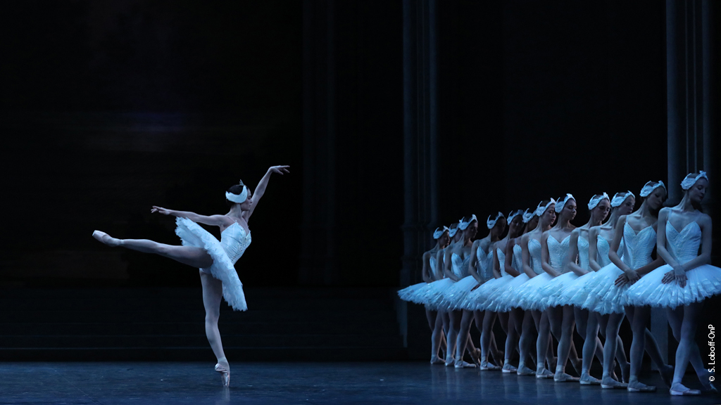 Odette performs an arabesque in front of the swan corps